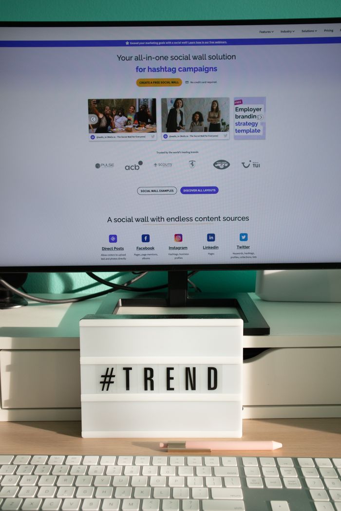 Un bureau épuré et contemporain avec une lightbox affichant #TREND et un écran d’ordinateur présentant une solution de social wall.